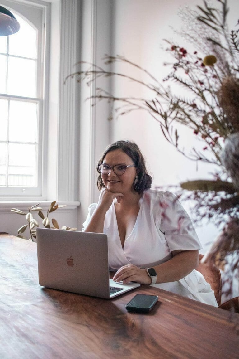 kreete tokman sitting in front of a laptop looking up and smiling